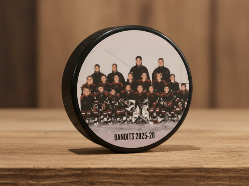 A custom hockey photo puck  featuring a printed team photo of the with the team name printed at the bottom, displayed on a wooden surface.