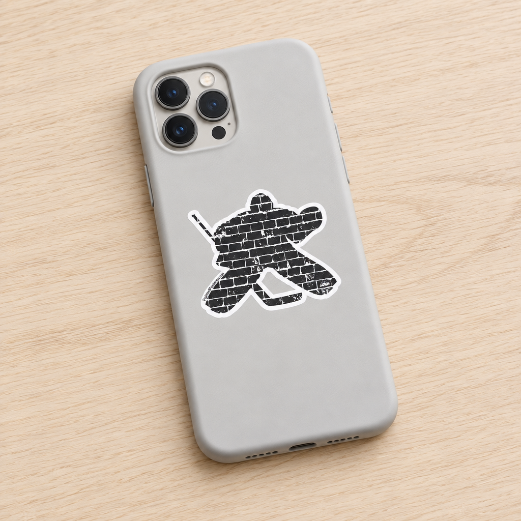 A light gray phone case with a distressed black hockey player silhouette graphic filled with a brick pattern, shown on a light wood background.
