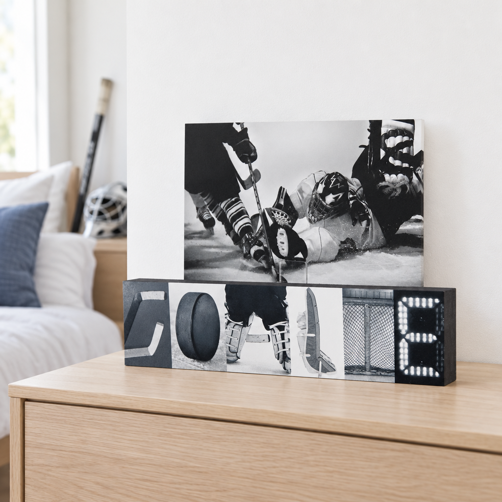 A hockey-themed photo display with the base spelling out GOALIE with hockey goalie photos and displaying a hockey goalie making a save photo.  This sits on a natural wood dresser in a goalie bedroom.