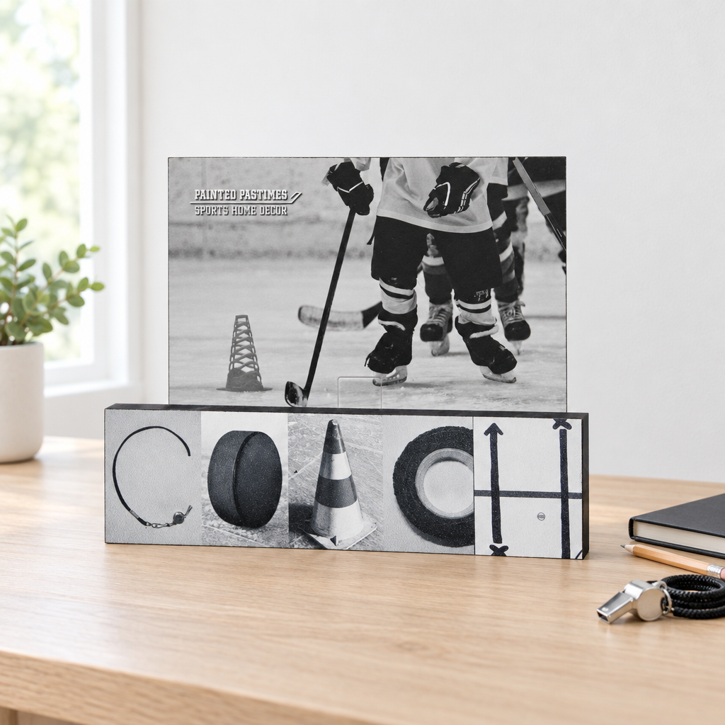 A black and white hockey-themed photo frame stand on a natural wooden desk. The top frame displays a black and white photo of ice hockey players, while the base spells out the word "COACH" with hockey coach photos.