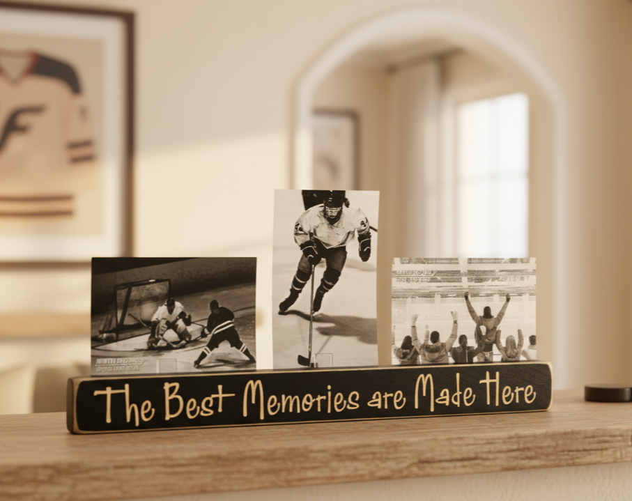 A wooden photo display sign on a shelf with three black-and-white hockey photos and the phrase 'The Best Memories are Made Here' in lasered lettering, set against a softly blurred indoor background.