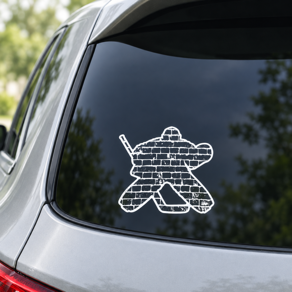 A white and black vinyl decal of a hockey goalie filled with a brick pattern, applied to the back window of a silver car.